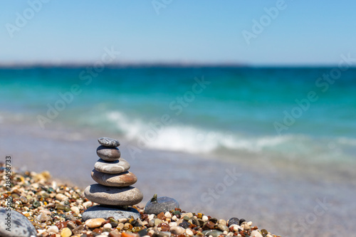 Pyramid of stones. Obo from pebbles. Stone tower on the beach against the blue sea. Balance  peace of mind  stones form a pyramid on pebble beach.