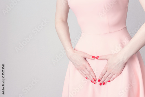 The woman has a stomach ache, the beginning of the menstrual cycle, woman touches belly, female hands, cropped image, menstrual period concept, toned, copy space
