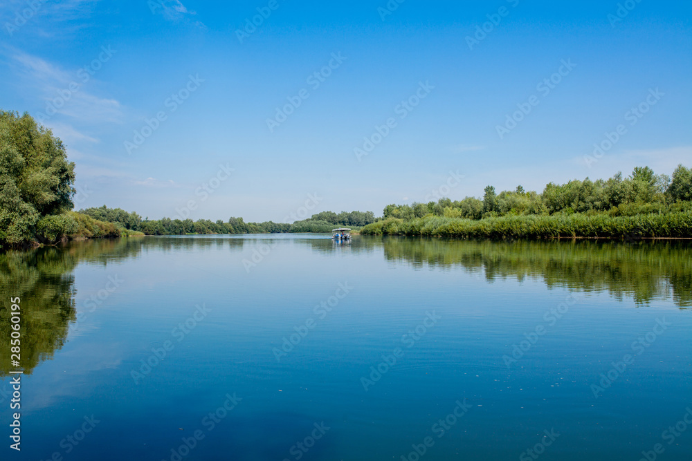 Blue beautiful sky against the background of the river. Clouds are displayed in calm water. On the horizon, the green bank of the Dniester, place for fishing