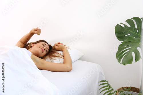 Young beautiful woman in her bed after waking up in the morning. Sleepy brunette female with satisfied facial expression. Healthy sleepiing habbits concept. Close up portrait, copy space, background. photo