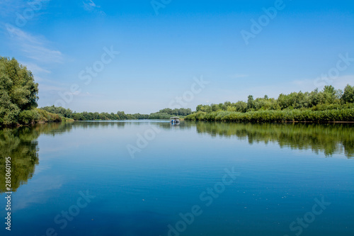 Blue beautiful sky against the background of the river. Clouds are displayed in calm water. On the horizon  the green bank of the Dniester  place for fishing