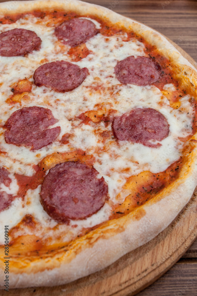 Italian Pepperoni pizza with salami on dark wooden background top view. Italian traditional food. Popular street food Italian Pepperoni pizza with salami on dark wooden background top view. Italian traditional food. Popular street food