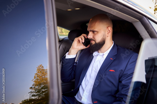 Successful young man talking on the phone in a car.