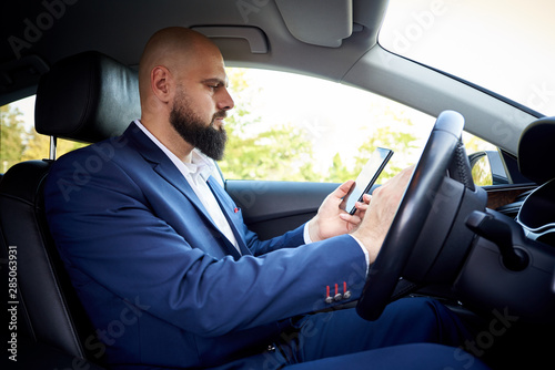 Successful young man with a smartphone in the car. © Viktoriia