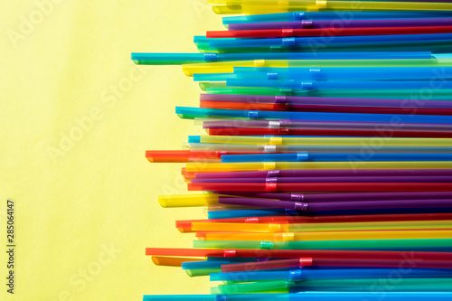 Colorful background. Flatlay. Multicolored drinking cocktail straws on yellow background. Colorful design and abstract.fashion minimal. flat lay.Drinking straw set of rainbow colored plastic tubes
