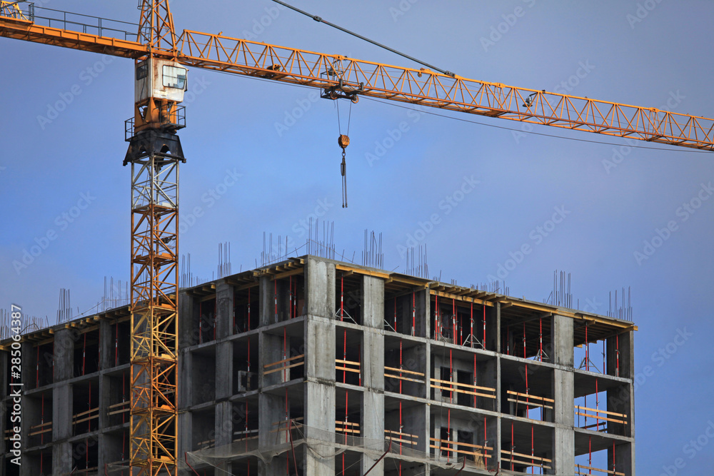 Crane and high-rise building. Construction site. The construction of modern apartment buildings. Property tax Crane and high-rise building. Construction site. The construction of modern apartment buildings. Property tax