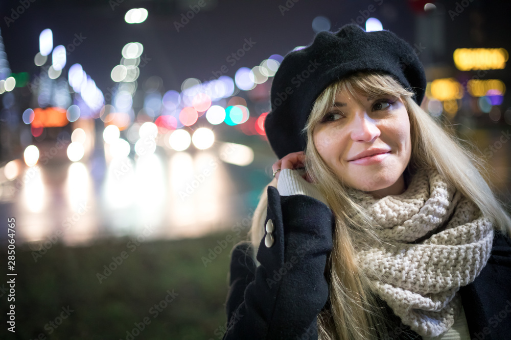 Pretty young stylish woman walking in the night city streets, bokeh illumination background Pretty young stylish woman walking in the night city streets, bokeh illumination background