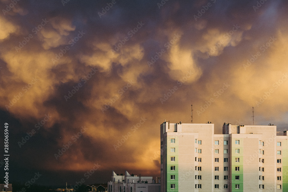blocks of flats against a cloudy sky with breaking sun rays
