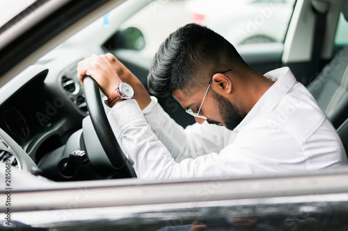 Фотография Closeup portrait tired young handsome man with short attention span, driving his car after long hours trip, trying to stay awake at wheel, isolated outside background