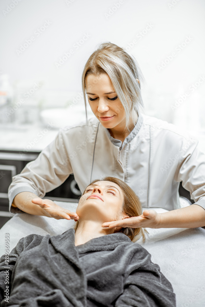 Cosmetologist making facial massage to a beautiful woman at the beauty salon. Concept of a lymph drainage therapy