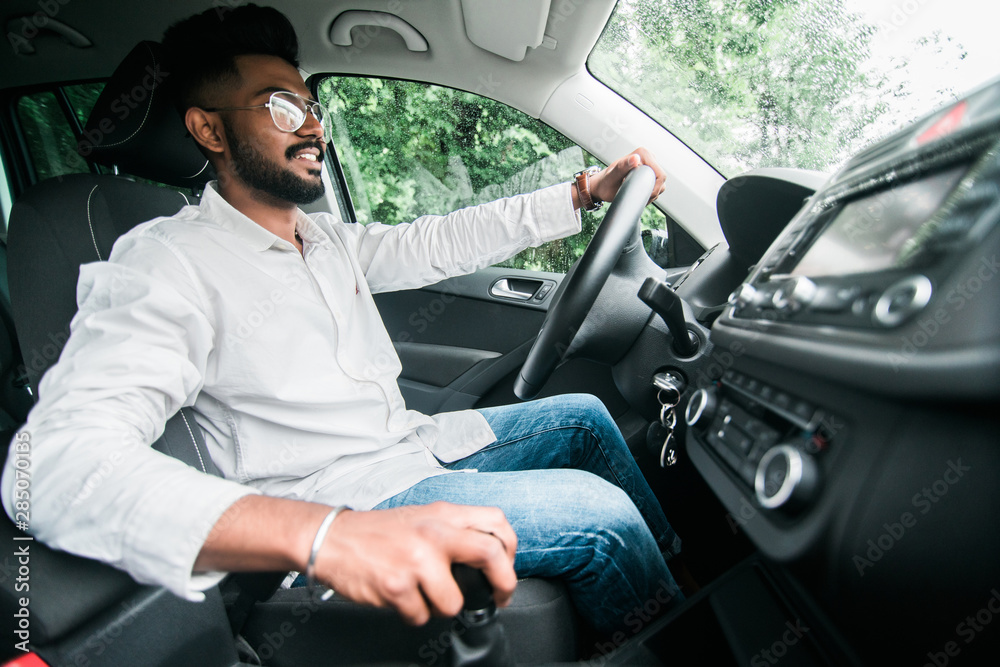 Young handsome indian business man drive car and change gear on highway Young handsome indian business man drive car and change gear on highway