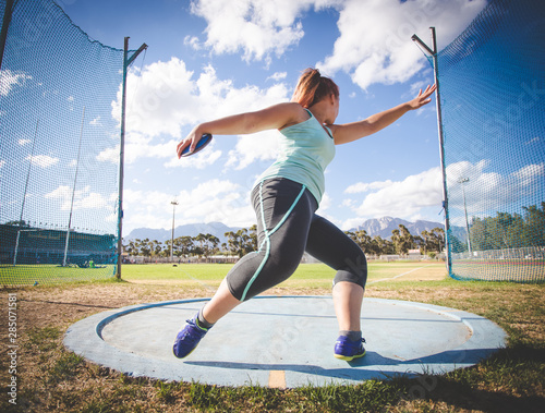 Wide angle action photo of a female discus athlete throwing a discus