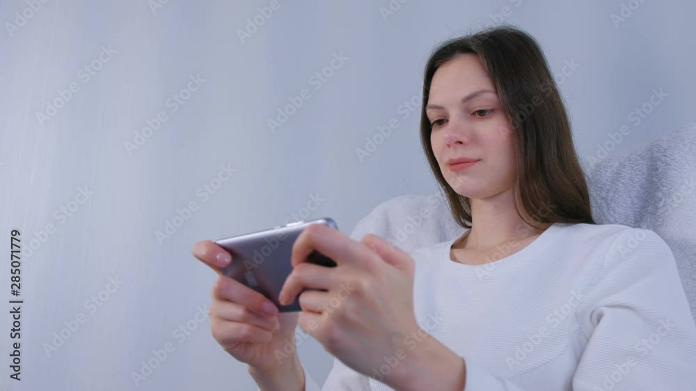 Young brunette woman is playing game on mobile phone Young brunette woman is playing game on mobile phone