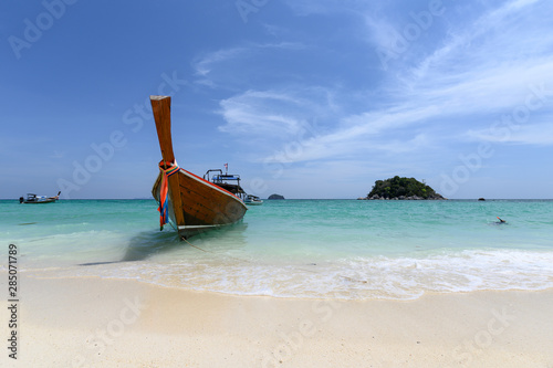 Wooden long-tail boat anchored on the beach in tropical sea
