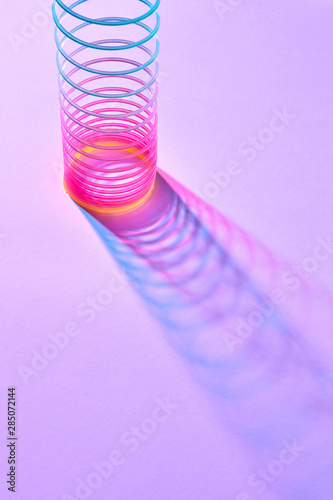 Stretching colored plastic slinky toy with shadows. photo