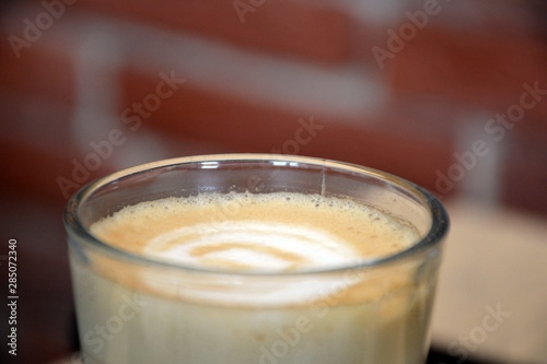  Aromatic coffee with a pattern in a glass cup on a brick wall background.