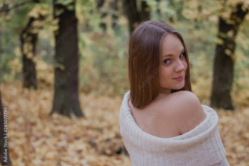 Naklejka premium Portrait of a beautiful, dreamy and happy girl with long wavy hair in knit sweater autumn. Nice weather