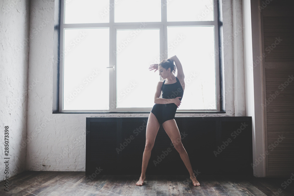 Plasticity slim woman dancing near window. Professional dancer enjoy dance. Lady Dancer Training Modern Ballet In Class. Contemporary dance performer. Daylight, silhouette beautiful body. Dance theme
