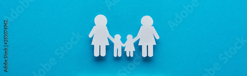 top view of paper cut lesbian family holding hands on blue background, panoramic shot photo