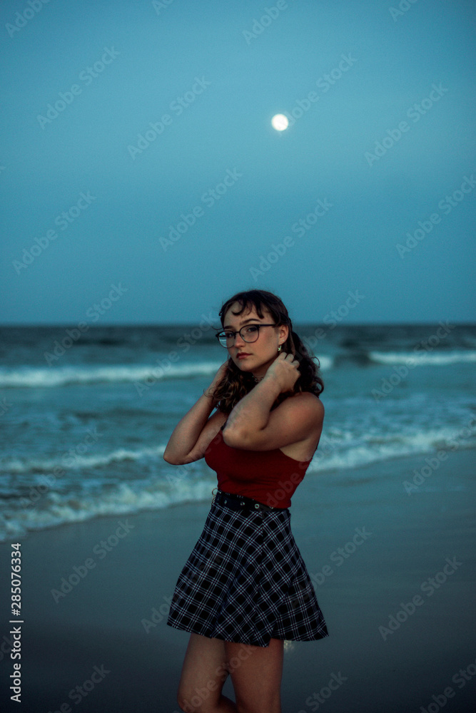 Young woman on the beach under the full moon Young woman on the beach under the full moon