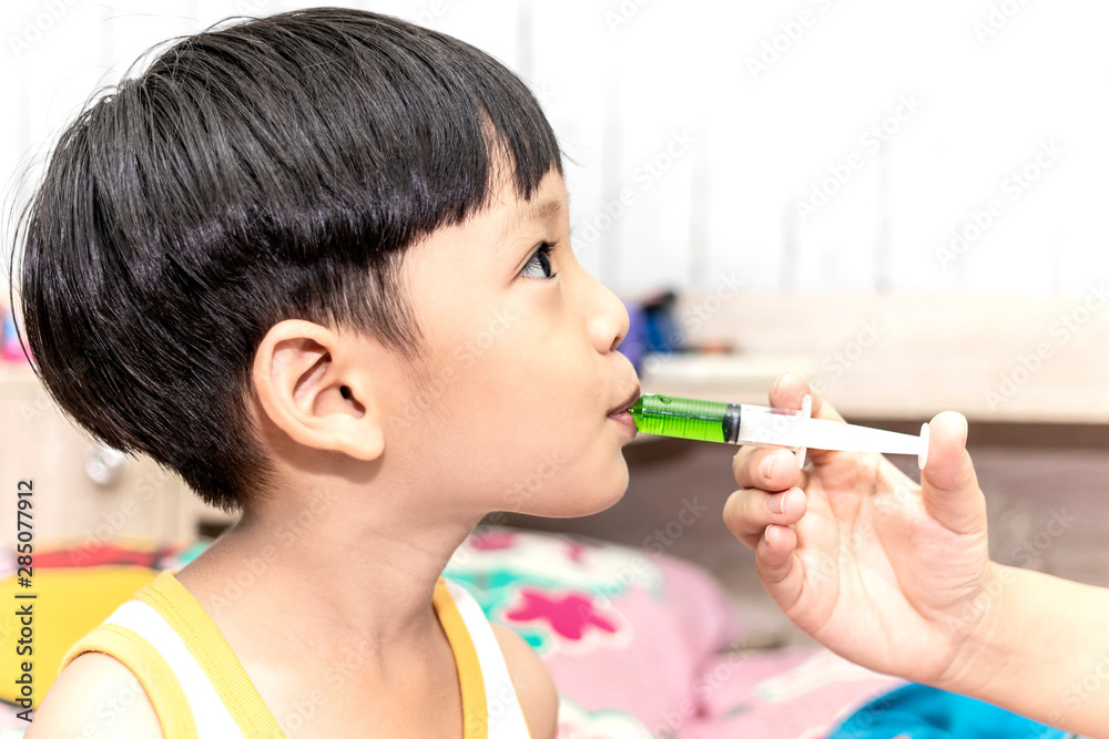 Mother giving medicine with syringe to asian little boy. Healthcare and medical concept. Mother giving medicine with syringe to asian little boy. Healthcare and medical concept.