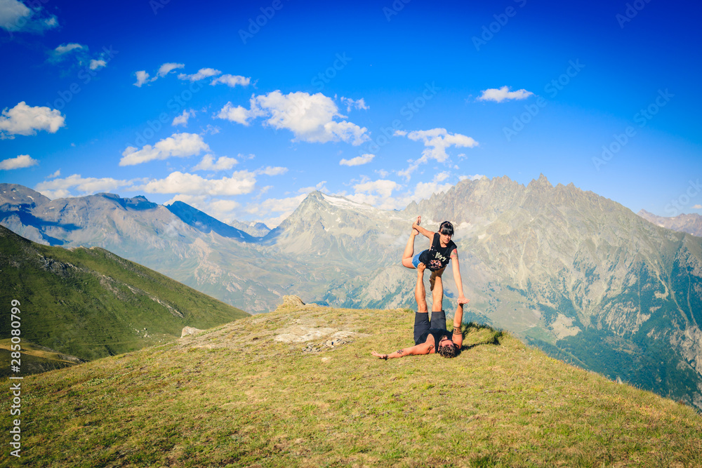  Giovane coppia pratica acroyoga e yoga all'aperto in montagna al parco