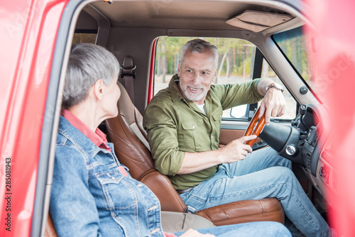 senior couple looking at each other with smile while sitting in car