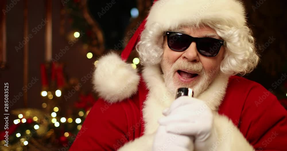 Santa Claus is singing with passionate into the microphone in the room decorated for Christmas. Christmas and New Year time. Santa Claus is singing with passionate into the microphone in the room decorated for Christmas. Christmas and New Year time.