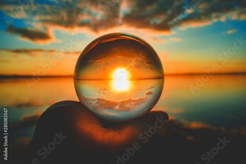 Creative crystal lens ball photography of the sunset with clouds blurred in the background