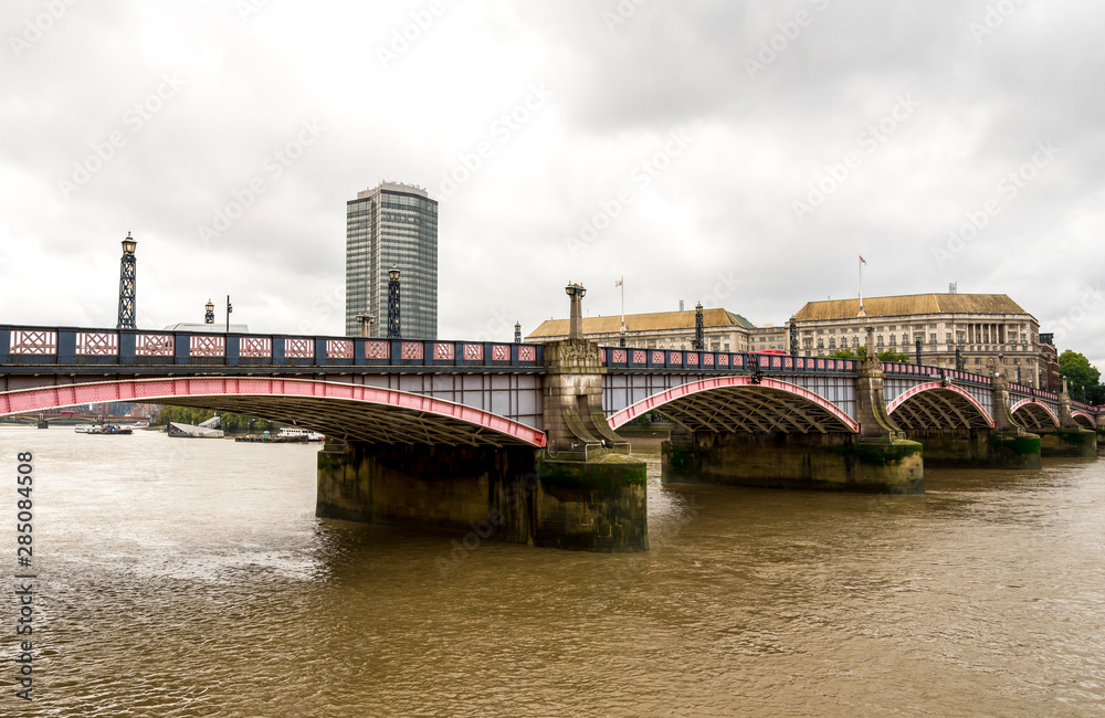 Arches of Lambeth bridge and brown waters of river Thames flowing through, London, England
