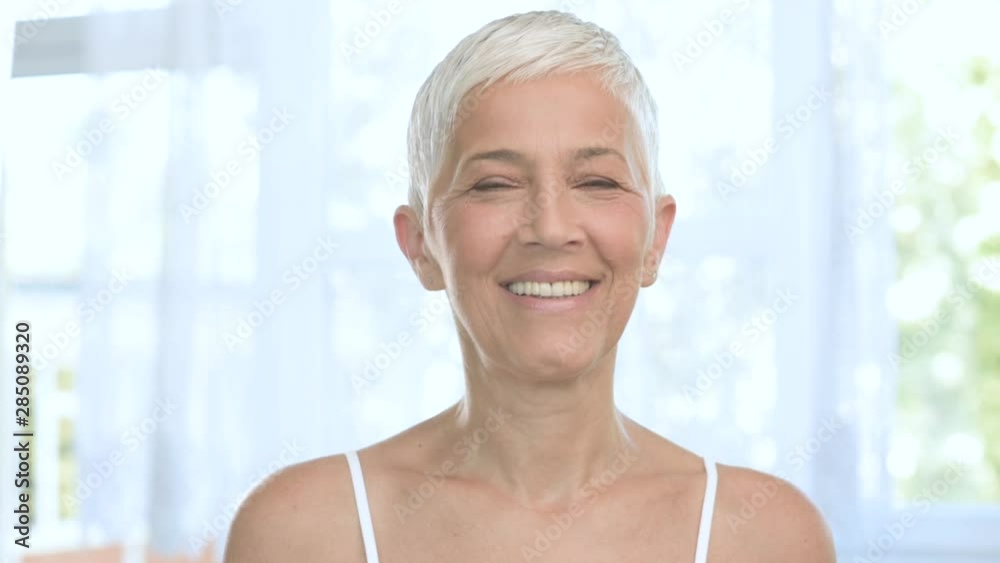 Beautiful smiling Caucasian senior woman posing with anti age cream.