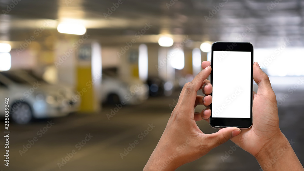 Man's hands holding smartphone blank screen in car parking.