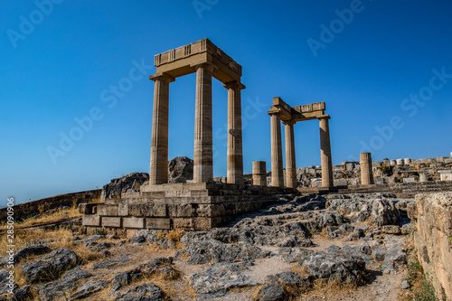 The Acropolis of Lindos in Rhodes, Greece at sunset. Scenic view of Doric columns from the ancient Temple of Athena Lindia setting sun light above the columns. Rhodes, Dodecanese, Greece, Europe