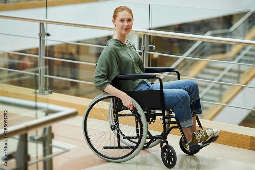 Portrait of young red-haired woman sitting in wheelchair and looking at camera she is a patient at modern hospital Portrait of young red-haired woman sitting in wheelchair and looking at camera she is a patient at modern hospital