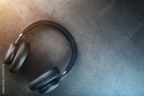 Wireless black headphones on a dark background with blue and orange backlight. On-ear headphones for playing games and listening to music tracks