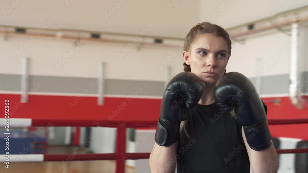 Close-up portrait shot of a professional female boxer in black gloves during the training. Rotation shot video Close-up portrait shot of a professional female boxer in black gloves during the training. Rotation shot video