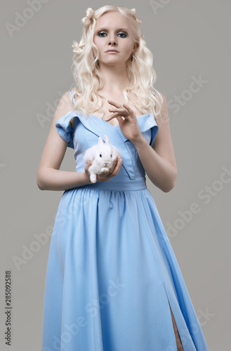 Albino blond girl in elegant dress posing with cute little rabbit © micro