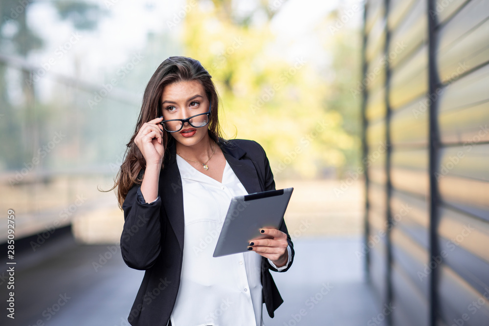 Business woman with tablet on hand standing near the office on break with glasses on head Business woman with tablet on hand standing near the office on break with glasses on head