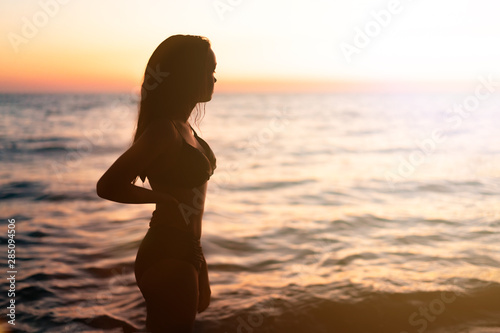 Silhouette of beautiful young gracile pensive woman with a freedom feeling at a beautiful sunset. Freedom and travel adventure happy feeling concept. © Juliaap