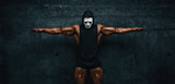Mysterious Muscular man hiding behind mask Flexing Muscles. Bodybuilder with mask on his face posing.