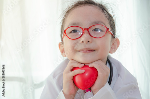 Asian girls wear pink shirts and red eyeglasses.Red heart in the hand, cute girl. © Siriluk
