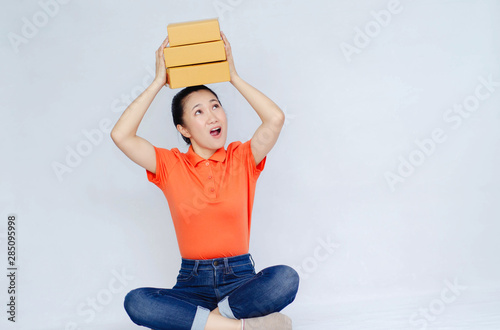 Asian women a orange shirt. she smiled and held several brown boxes at the same time isolated white background.Women send parcels.