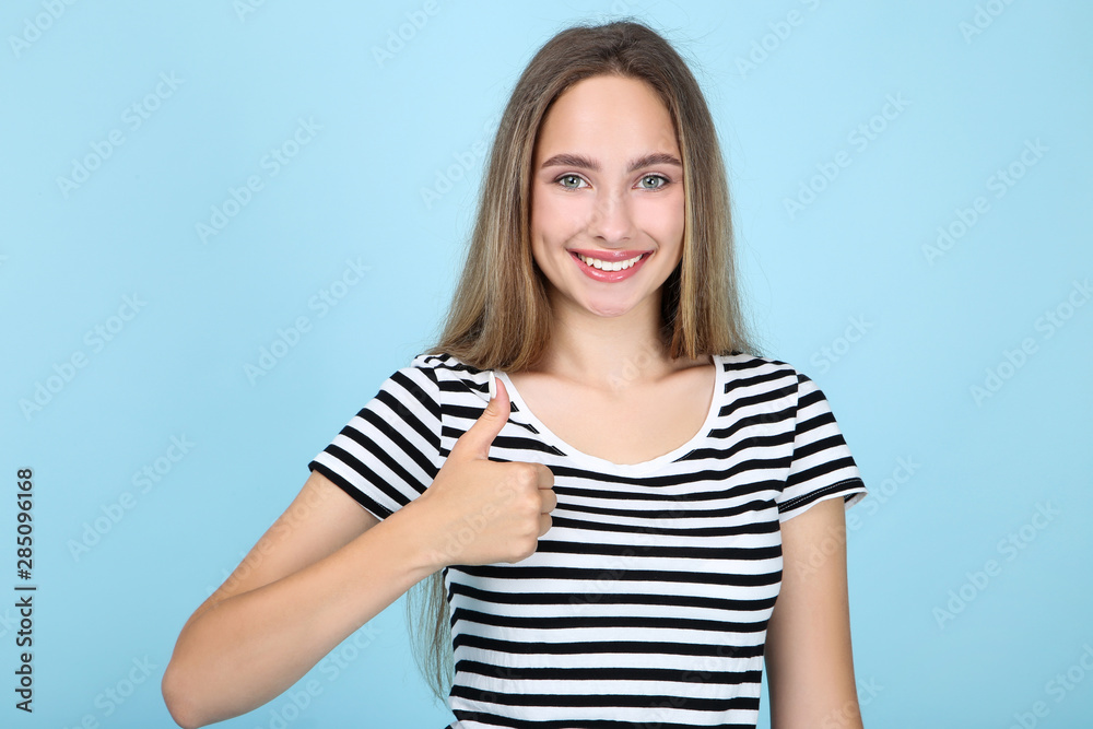 Beautiful young woman showing thumb up on blue background Beautiful young woman showing thumb up on blue background