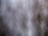 ..Raindrops on the surface of window glass with a blurred background.