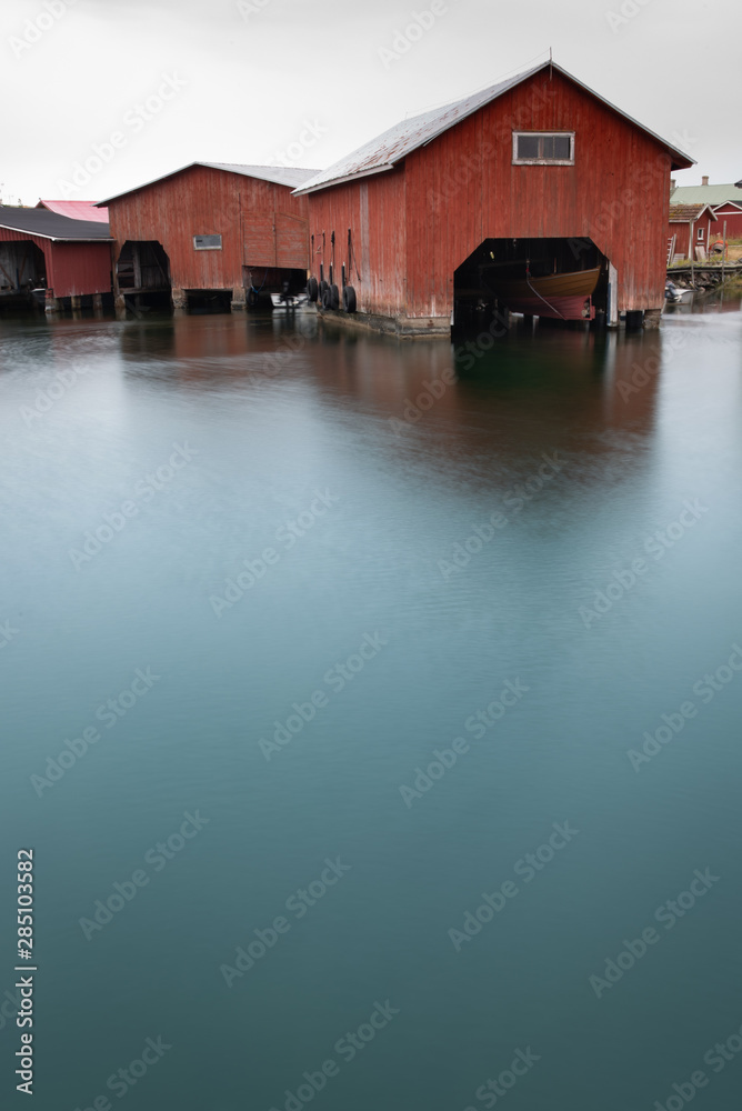 Fototapeta premium Boathouse in calm harbor water