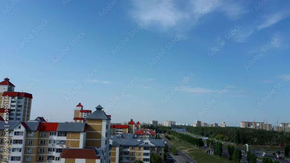 Aerial view of growing city in sunlight. Drone view of new building complex in city center with houses and roads under cloudy sky Aerial view of growing city in sunlight. Drone view of new building complex in city center with houses and roads under cloudy sky