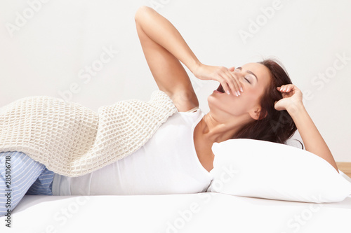 Young woman yawning on bed photo