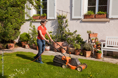 Germany, Stuttgart, Woman mowing lawn photo