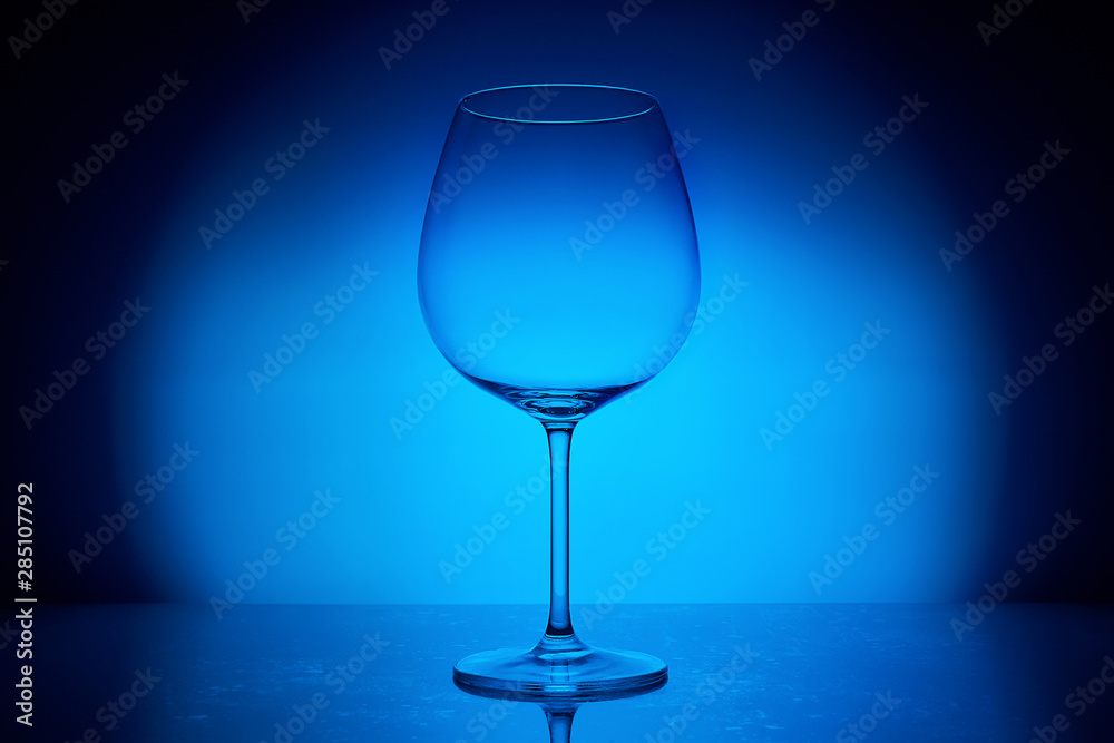 elegant empty wine glass on blue lighting background