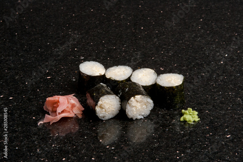 Sushi rolls on black marble background. Fresh Hosomak, Maki, Nigiri, Tempura, Uramaki, Philadelphia pieces with rice, nori and fish. Japanese cusine, Asian food.
